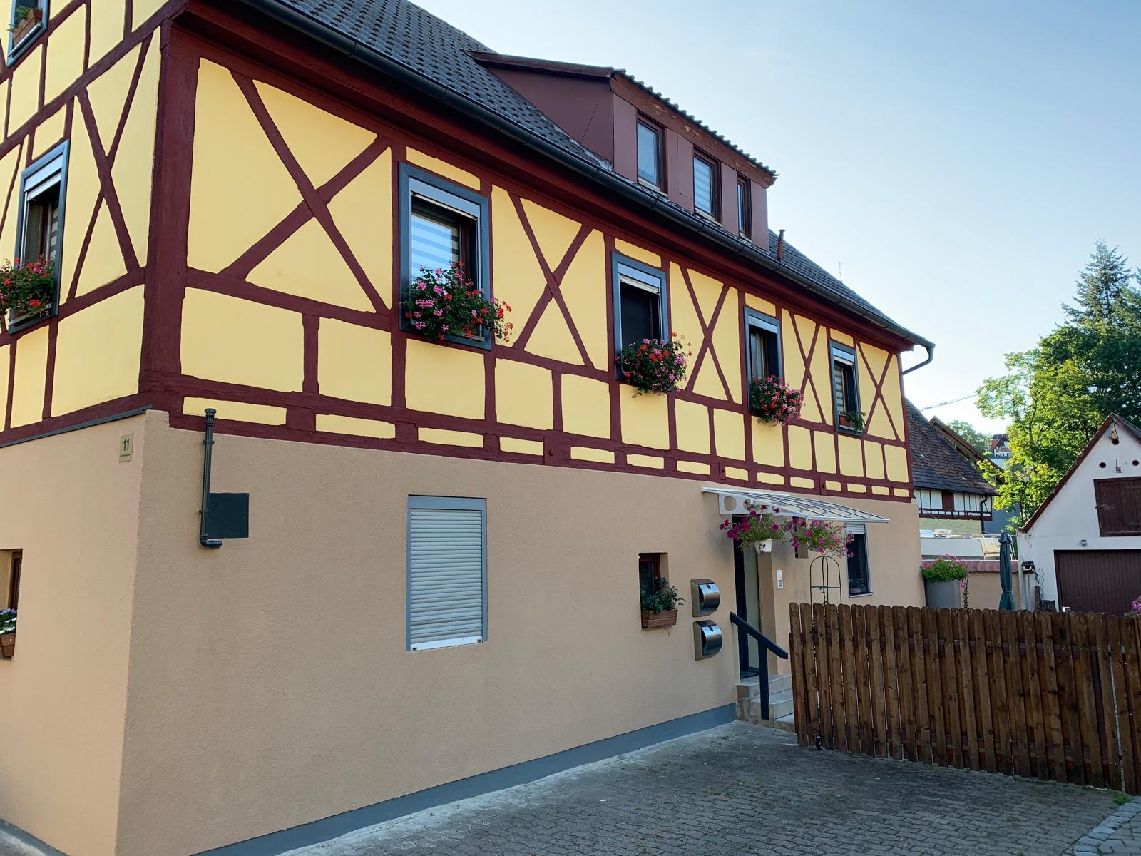Sanierte Fachwerkfassade in Gelb mit rotbraunen Balken