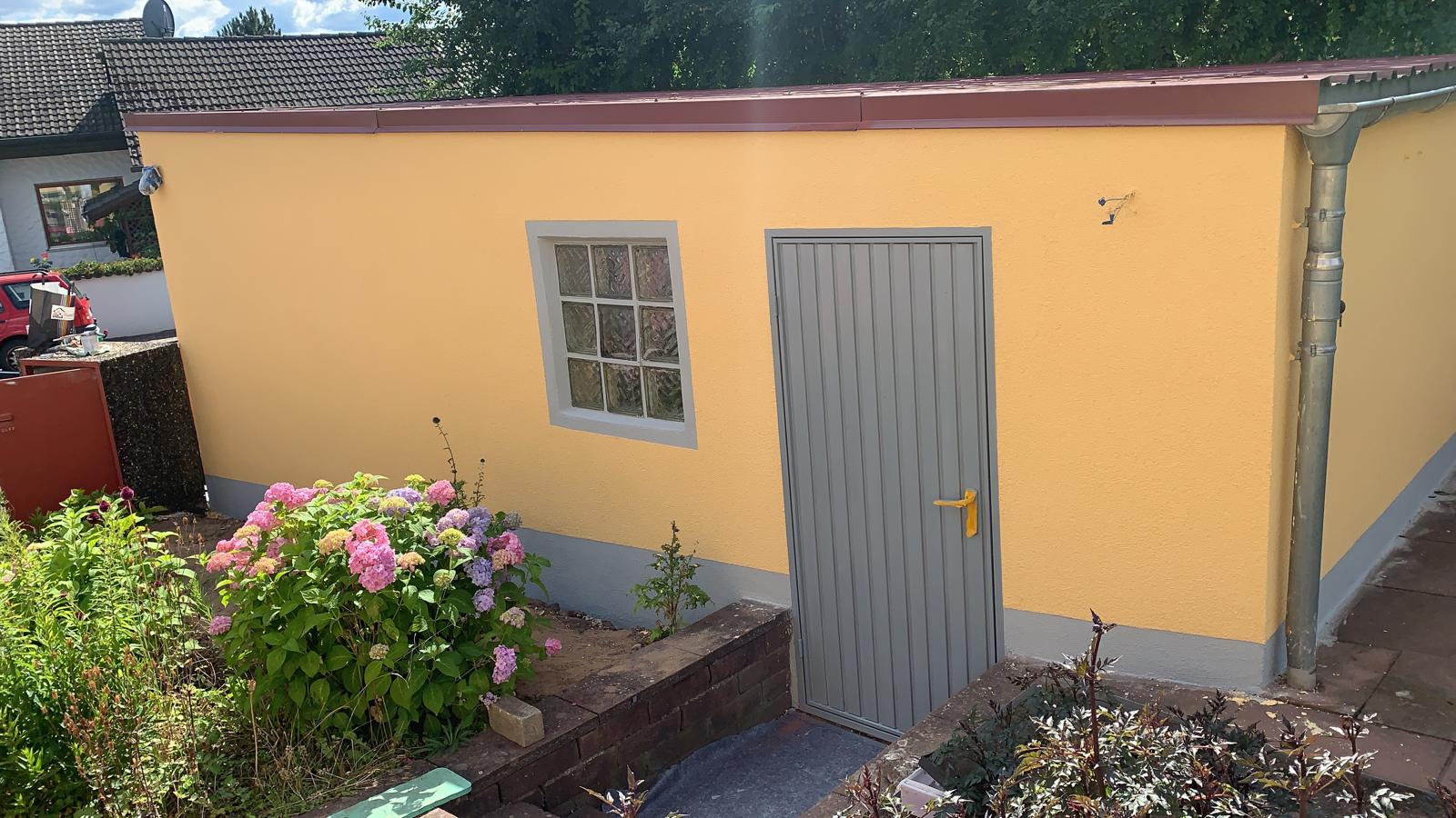 Fassade Nebengebäude in warmem Gelbton mit grauen Sockel- und Türakzenten
